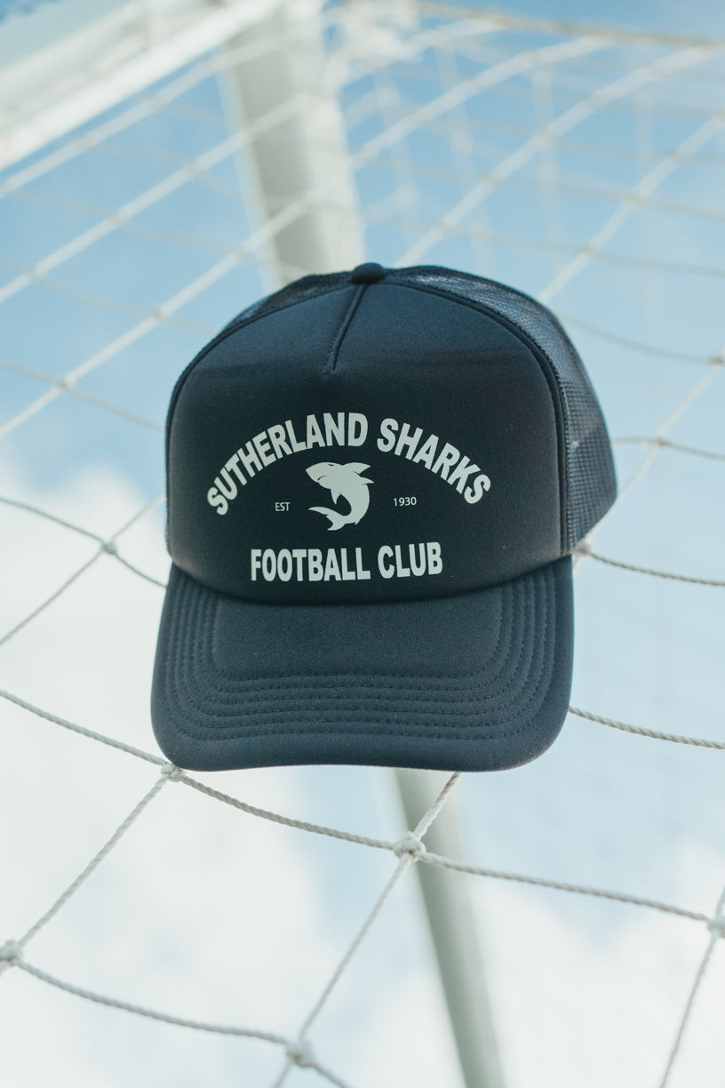 Black cap with 'Sutherland Sharks Football Club' text on a sports field background