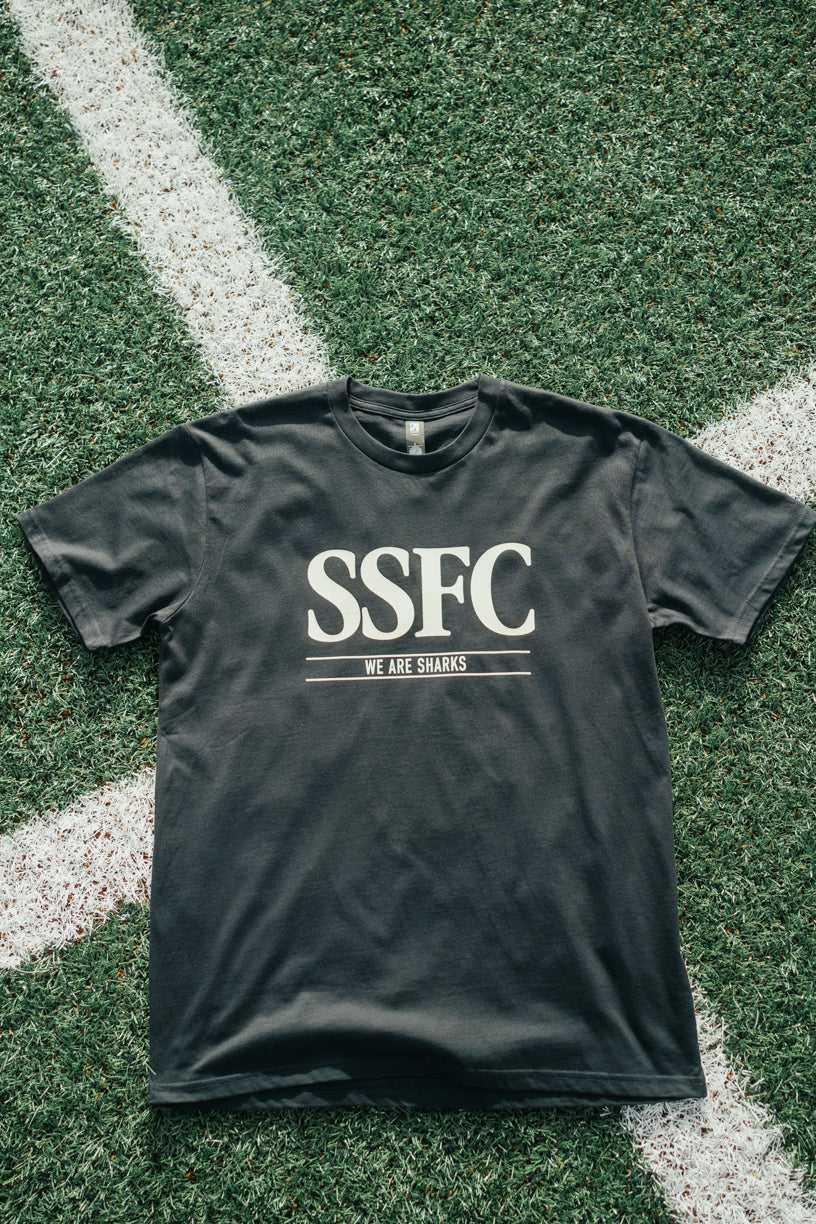 Black t-shirt with 'SSFC' and 'We Are Sharks' text on grass