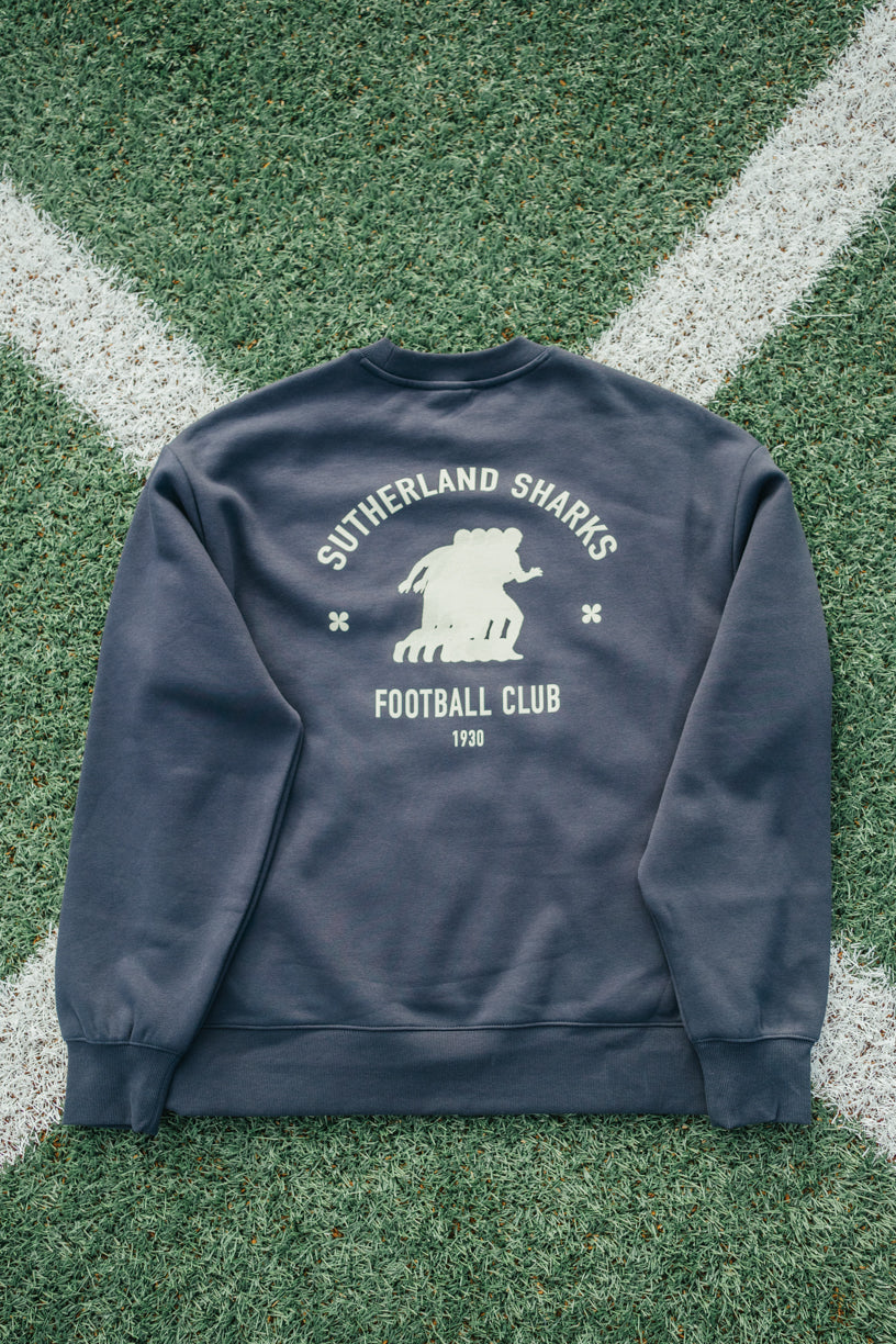 Navy blue sweatshirt with 'Sutherland Sharks Football Club' print on grass